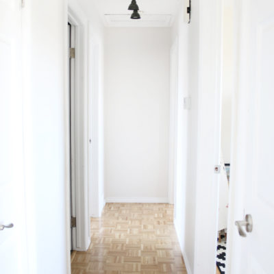 Interior hallway with brown tile floor and white walls.