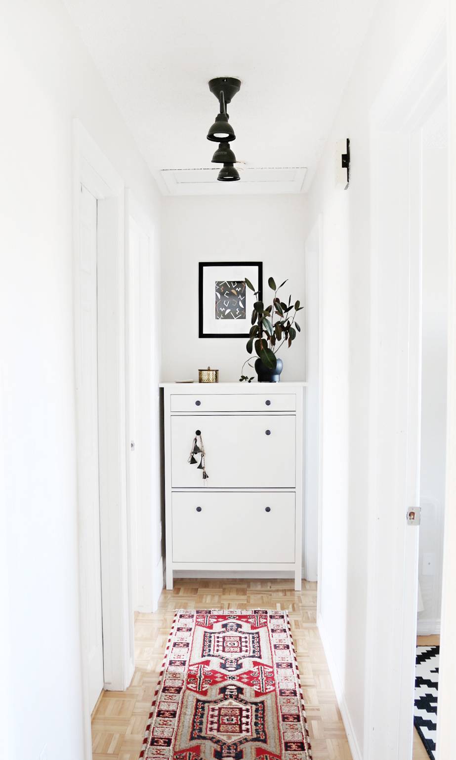A rug on the hallway with white walls.