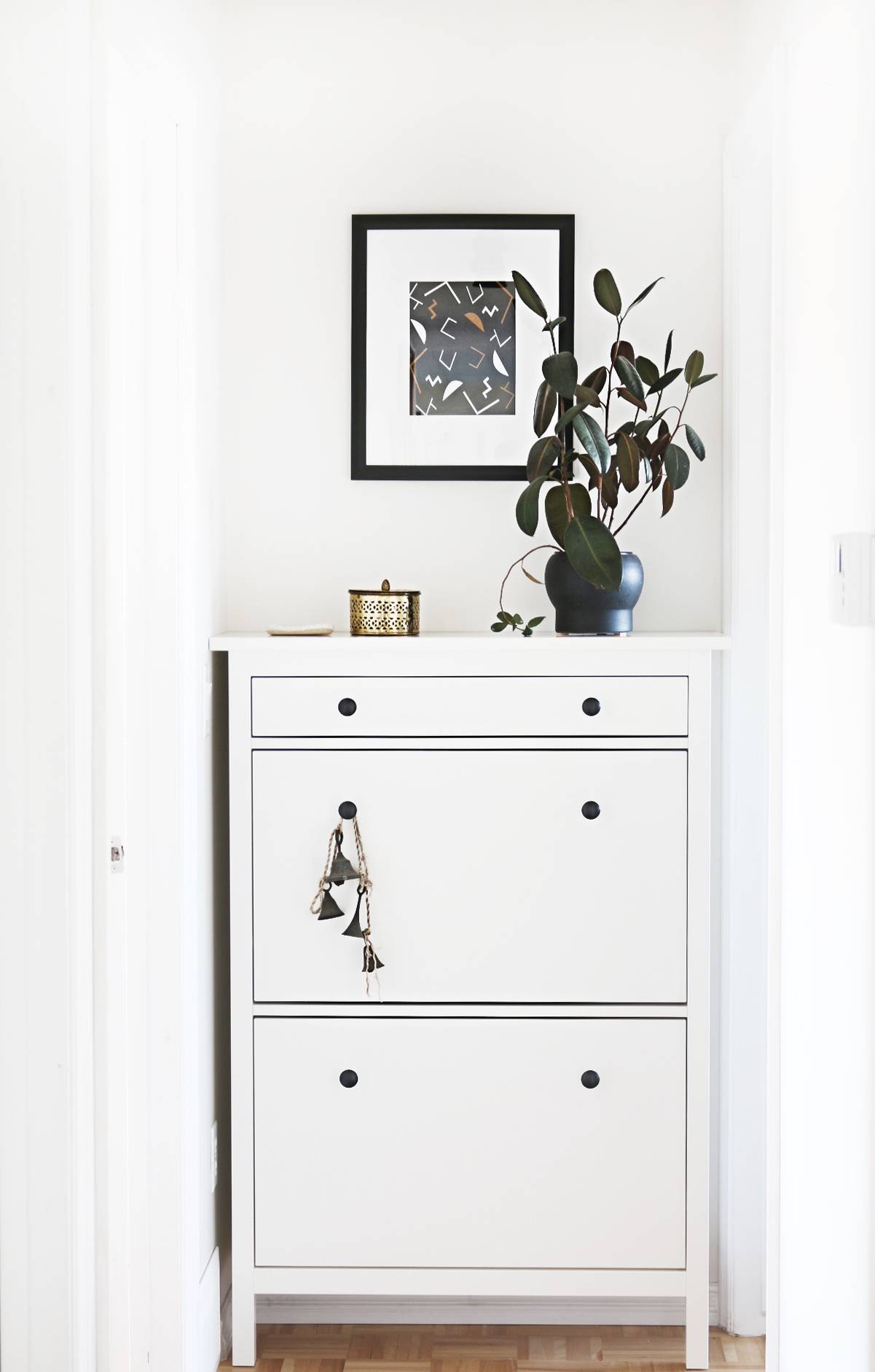 A white dresser has a vase of flowers with a picture above it.