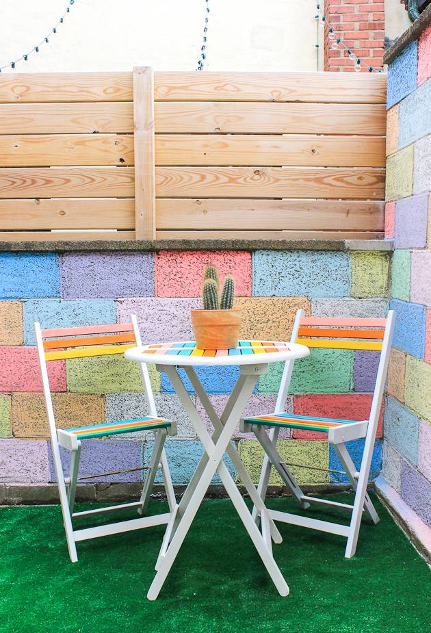 Colorful tables and chairs sit next to a colorful wall with wood.