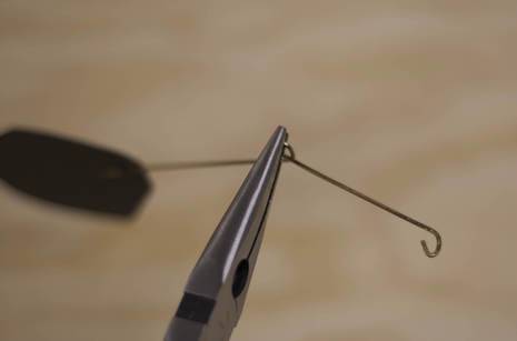  Holding the connected rod and shape so the shape’s face is perpendicular to the floor, make an open-ended hook at the opposite end, bending the wire towards you .