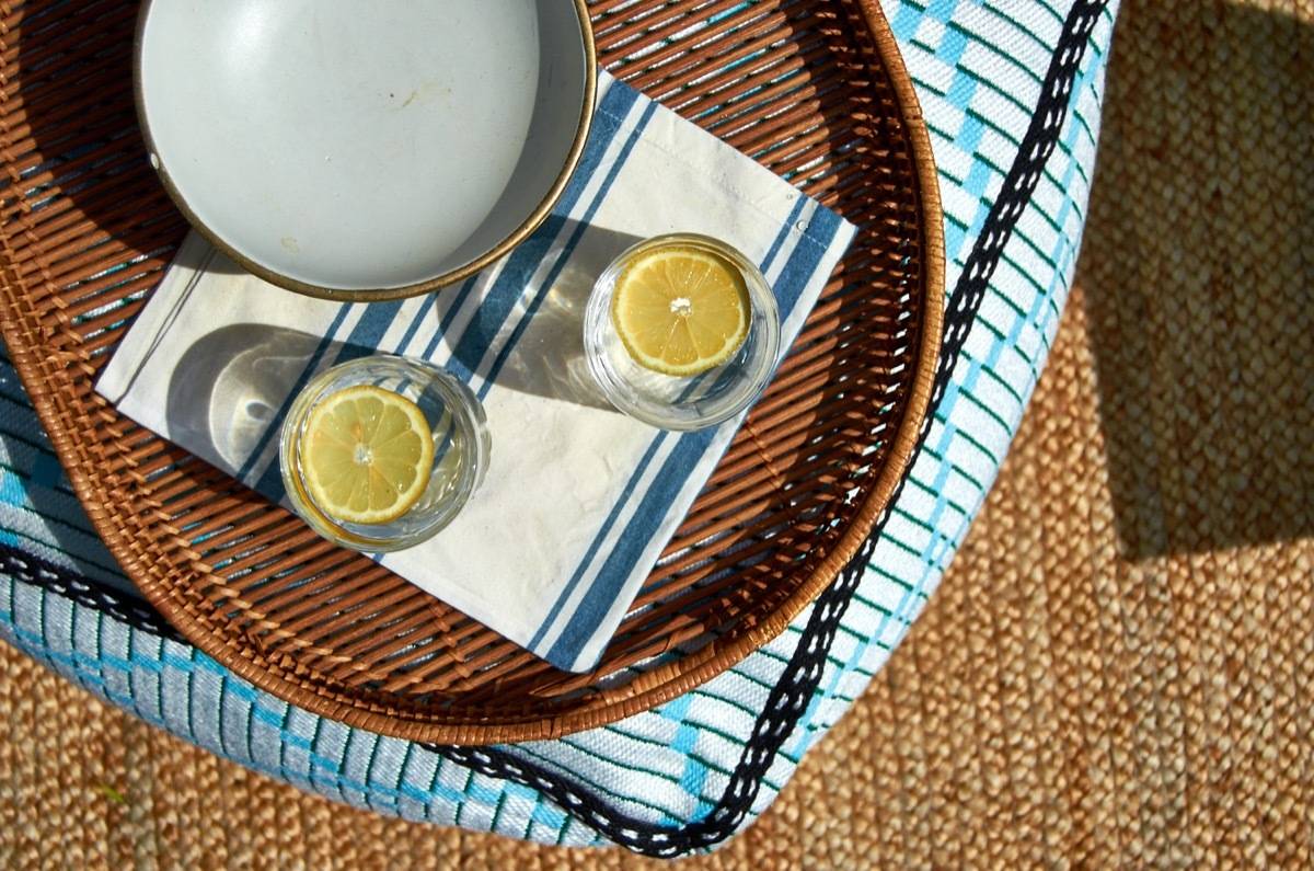 A white bowl on a blue and white napkin next two to glasses of ice water with lemon