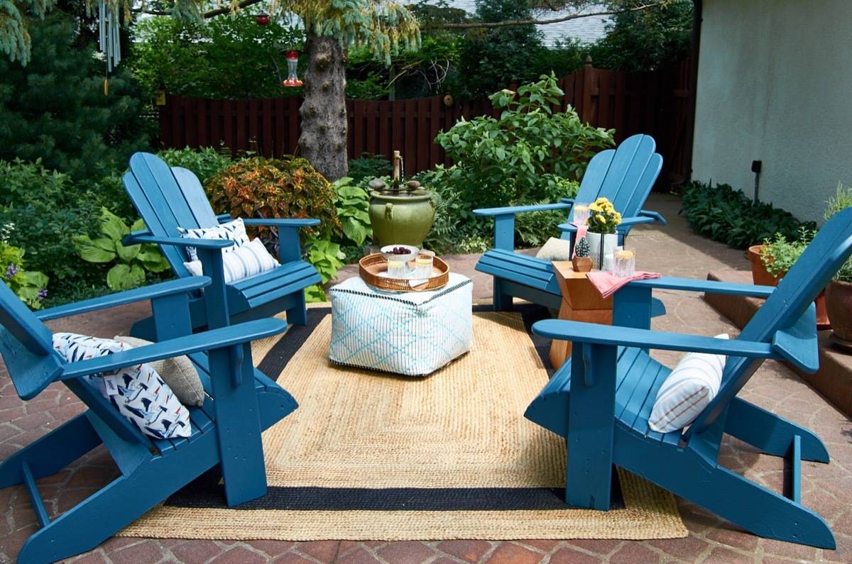 A cute patio with bright blue Adirondack style chairs,