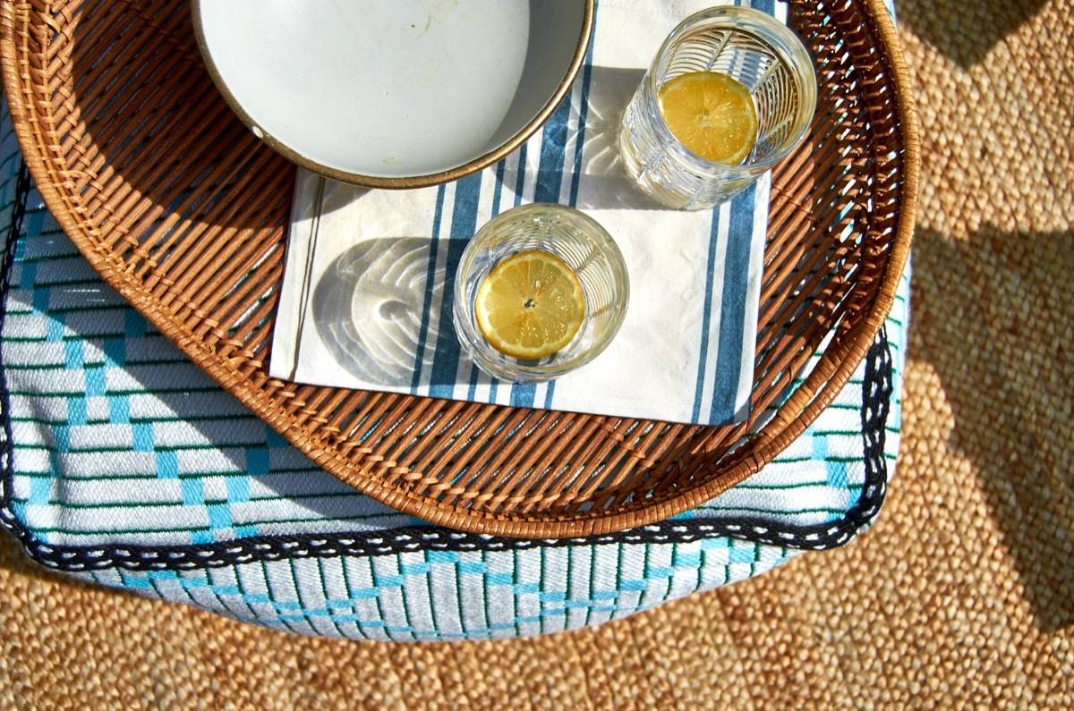 Two mostly empty glasses with orange slices in the bottom sit on a tray on a patio table.