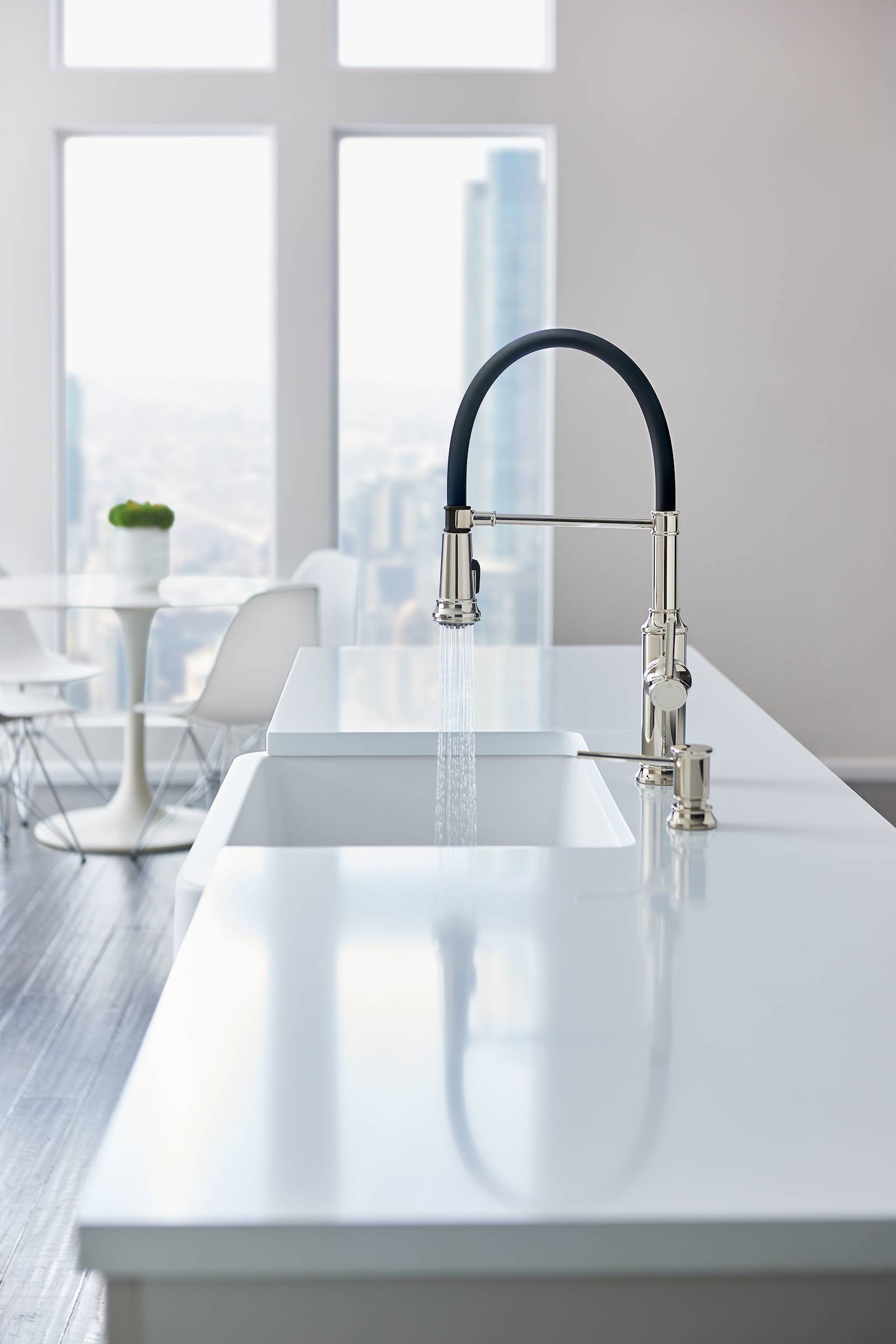 A white kitchen island sink with a black no touch faucet in a skyscraper dining room.