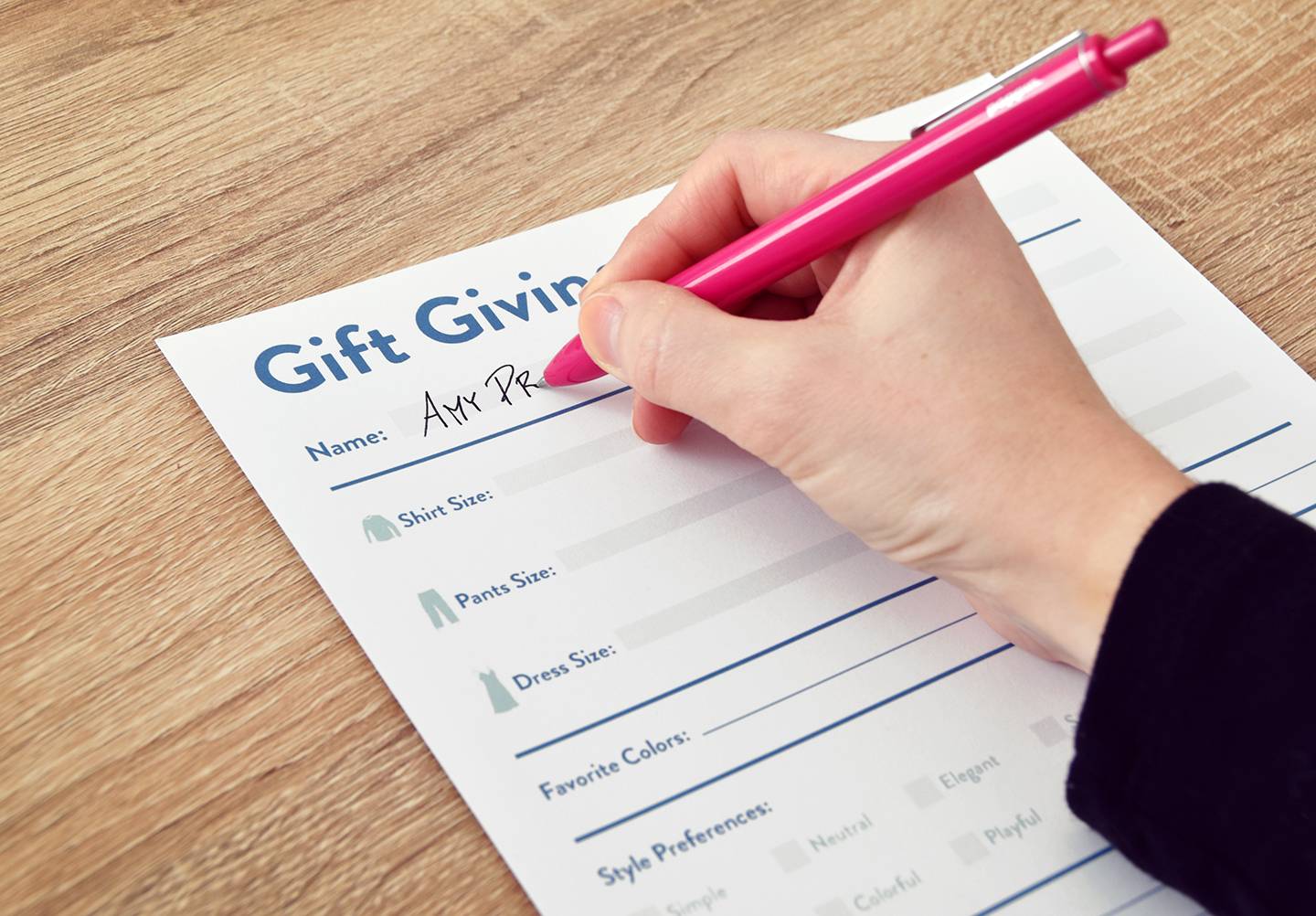 Person is writing on a gift giving sheet using pen.