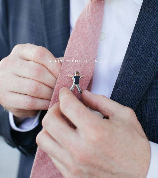 A man in a suit is straightening a salmon colored tie.
