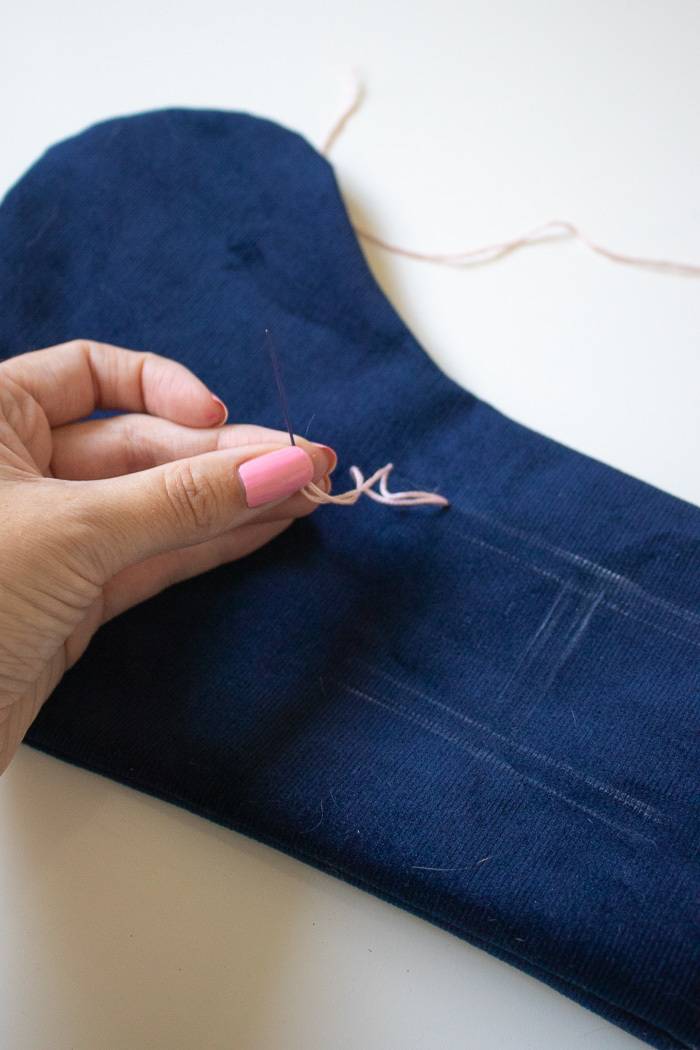 A hand that is sewing blue fabric