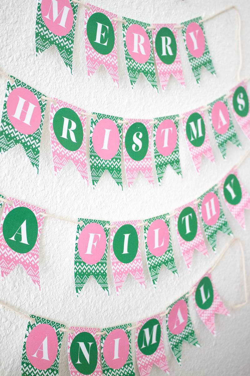 Pink and green Christmas bunting is hanging on a wall.