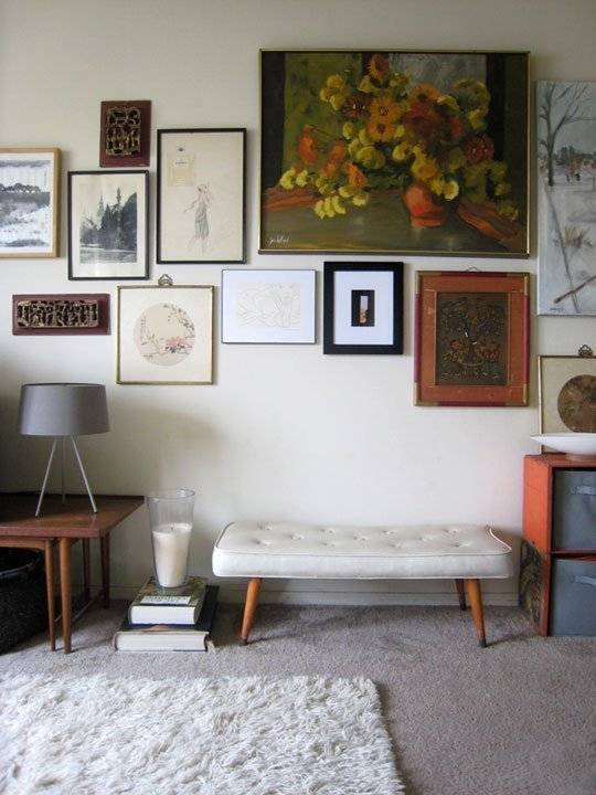 Pictures decorating the wall of a room with a light colored rug on the floor.