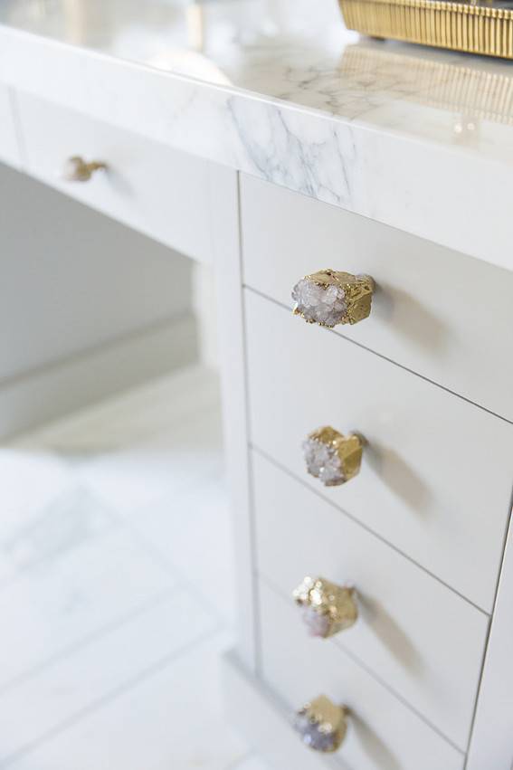 A White desk has decorative knobs and marble material.