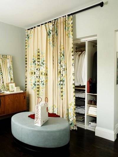 A yellow curtain hides the wardrobe section in a room.