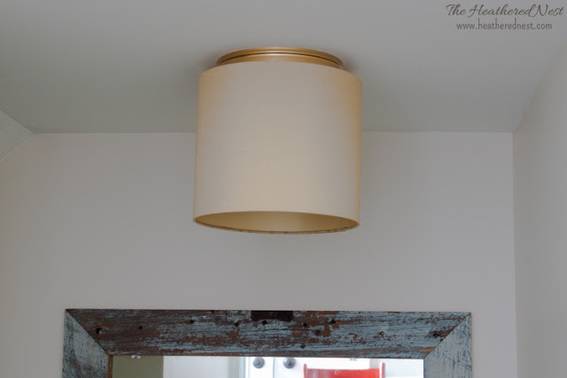 The shade of a light fixture covers the bulb on the ceiling.