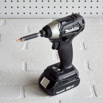 A black Makita drill sits on a white workspace.