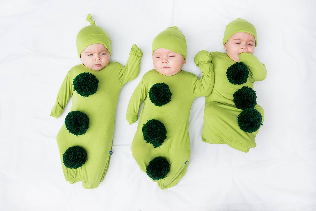 Three babies are dressed in lime green outfits with black balls sewed on them.