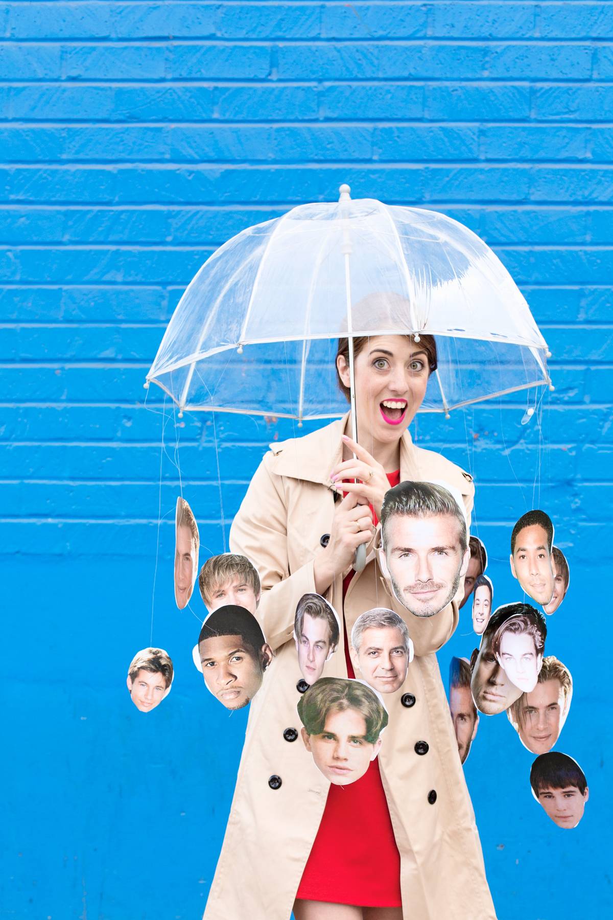 A person has a clear umbrella with faces hanging from it.