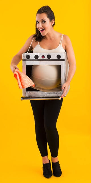 A woman holding a cardboard over in front of her pregnant belly.