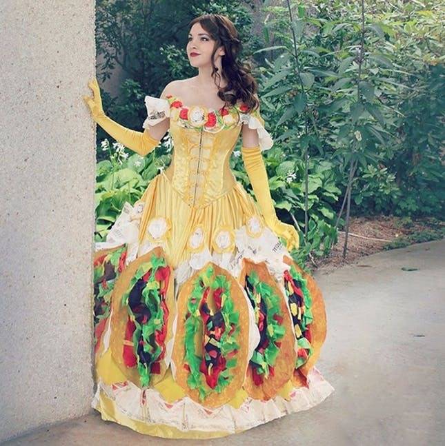 A woman wears a yellow dress with decorative tacos on the bottom.