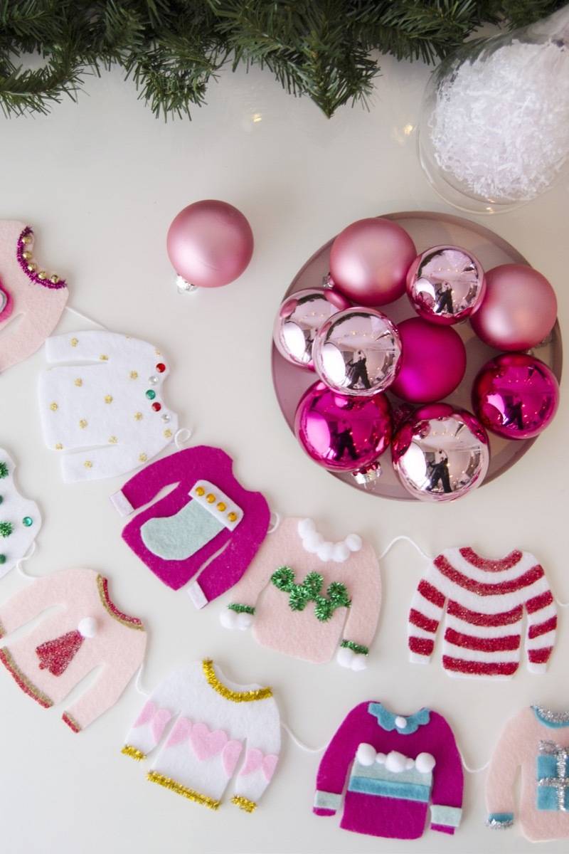 Green tree decorations are above pink ornaments and clothing crafts.