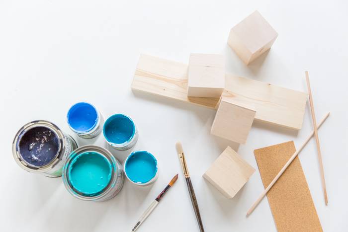 Blue shaded color tins, brushes, and wooden boxes in the white background.