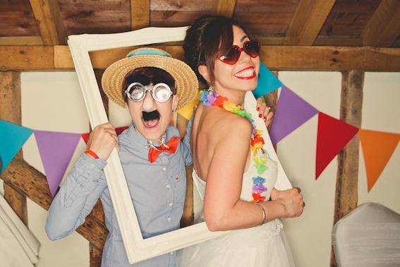 A couple pose in festive costume in a fake photo frame.