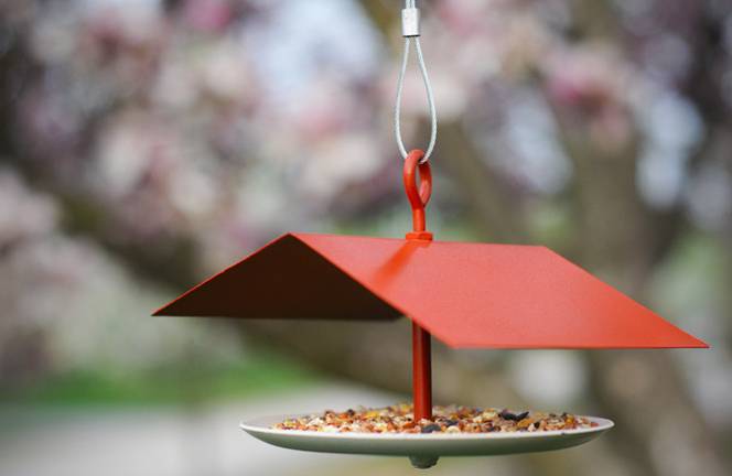 A bird feeder with a red roof