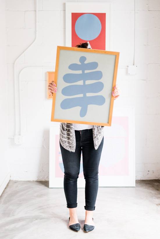 A person is holding up a blue and white picture with a yellow frame.