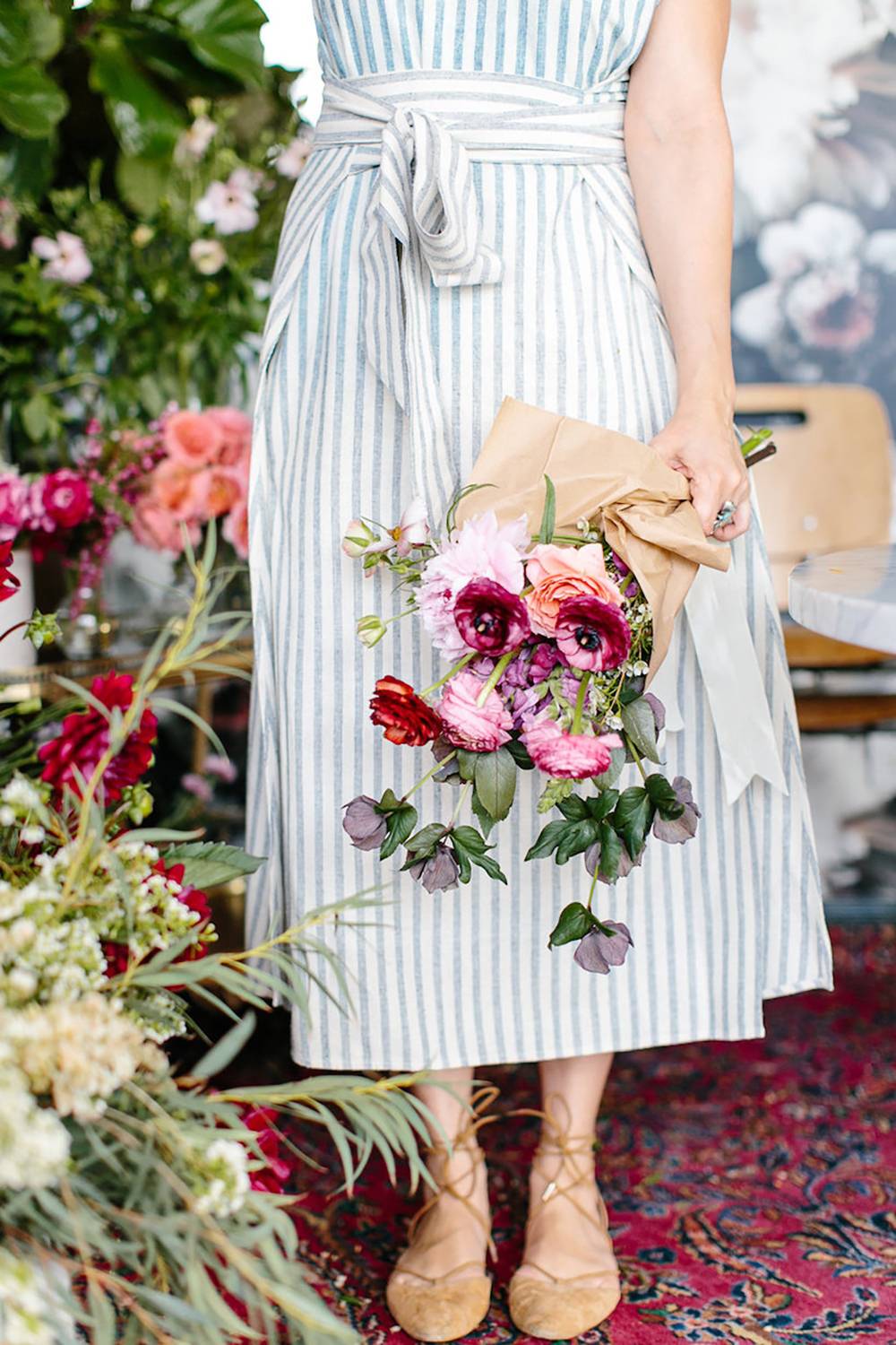 The lower half of a woman in a blue dress holding a bouquet.