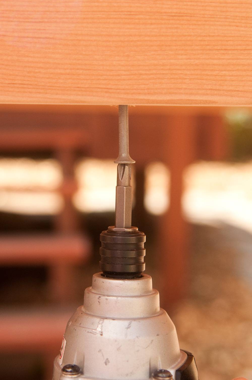 White screwdriver drilling a nail into a piece of wood to make a workbench.