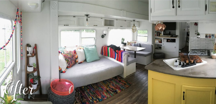 Daybed adorned with colorful pillows near a kitchen nook and well laid out kitchen.