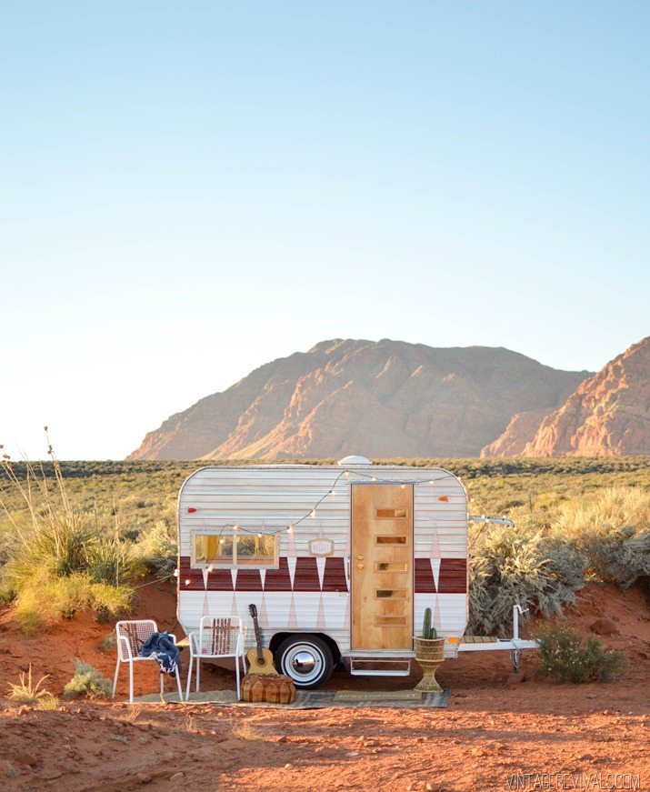 A camper vehicle parked in the deserted area with chairs, table and guitar.