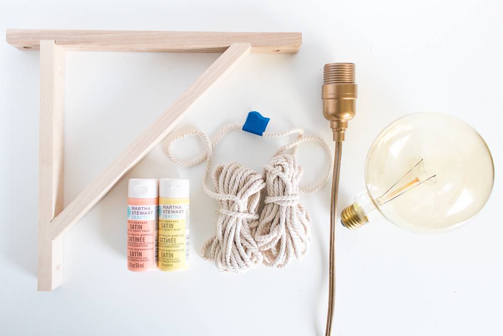 A wooden brace, two plastic containers, two bundles of rope, one electric outlet and one round light bulb.