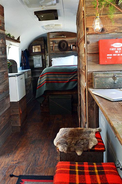 The neat and tidy inside of a camper with red plaid on the stools.