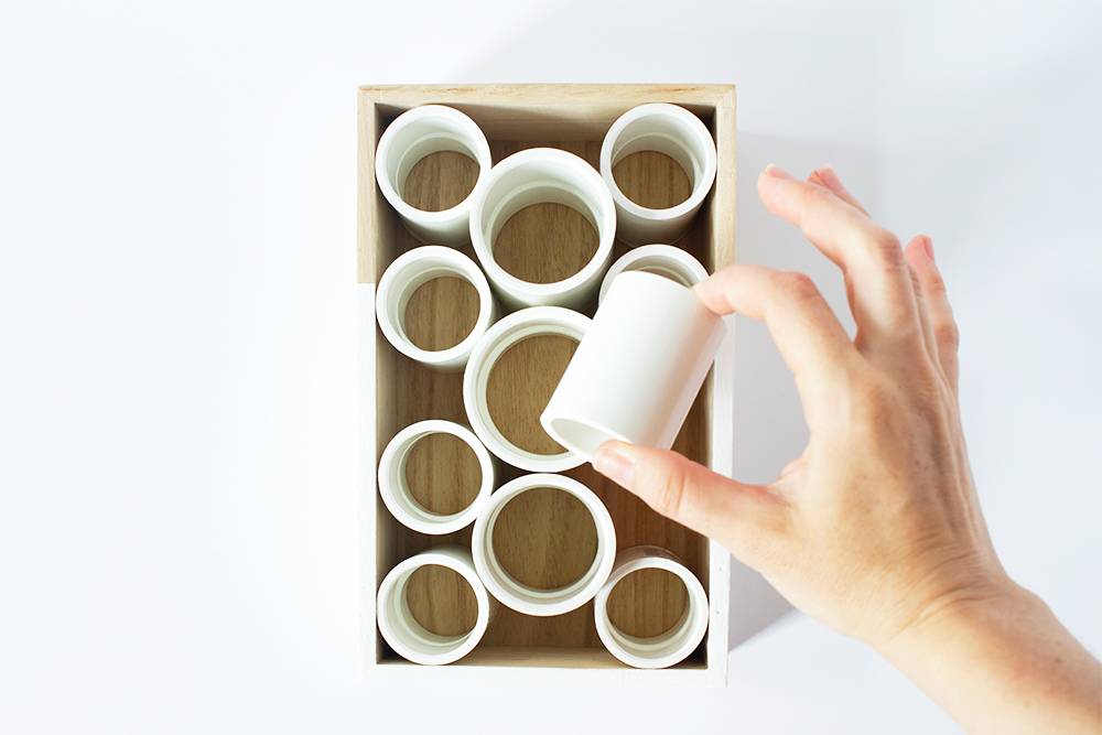 A person holding a white pipe from a box.