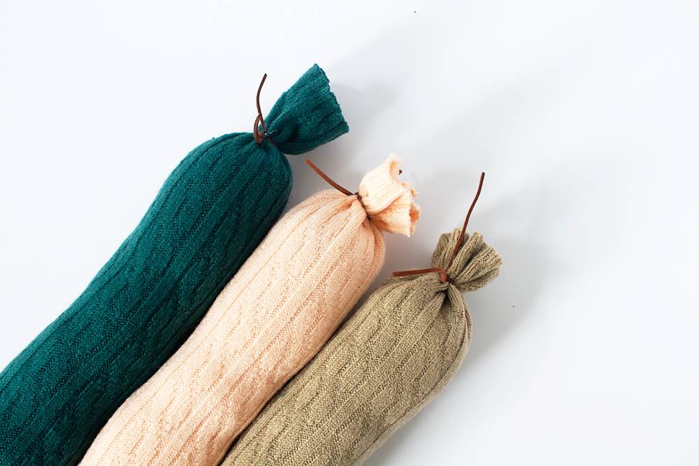 Stuffed tubes of fabric tied with a string sitting next to each other on a white background.