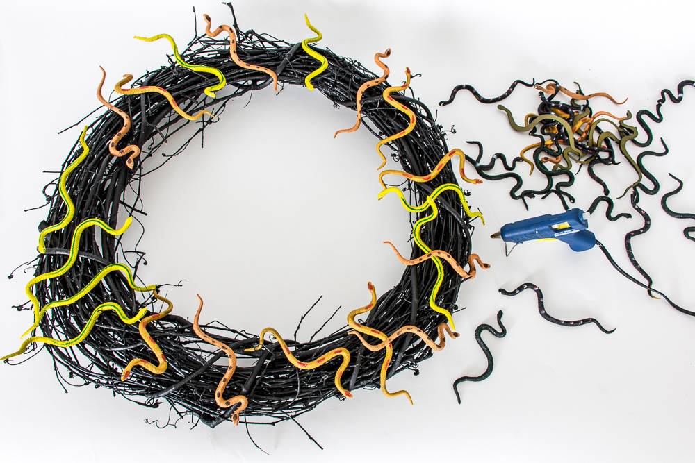 Glue the plastic snakes to the grapevine wreath
