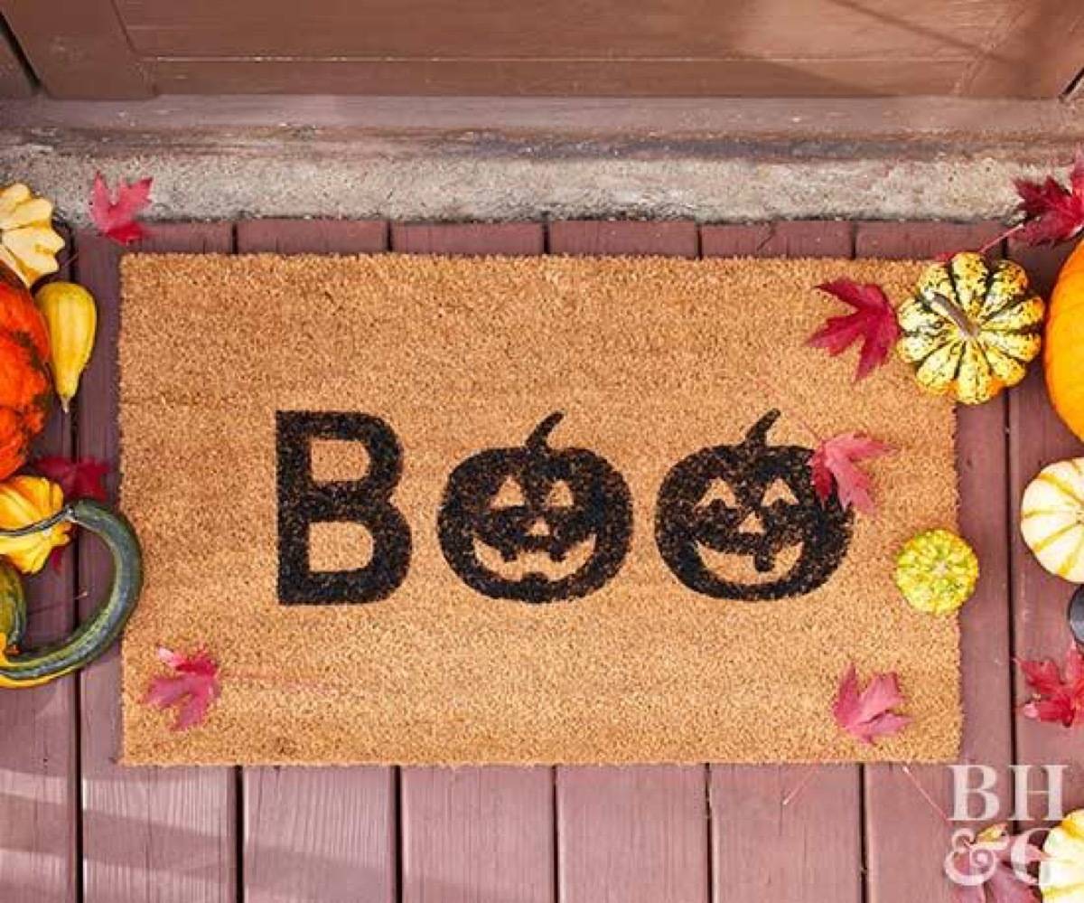 A door matt shows the word BOO with the Os shaped like jack o lanterns.