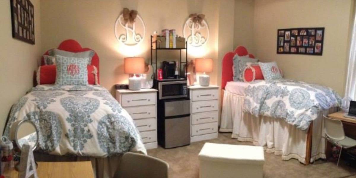 A room having two separate beds and a refrigerator and bedside tables in the middle.
