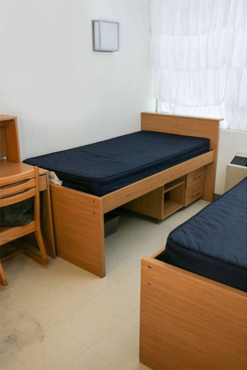 Two twin beds with wooden frames set up in a small room.