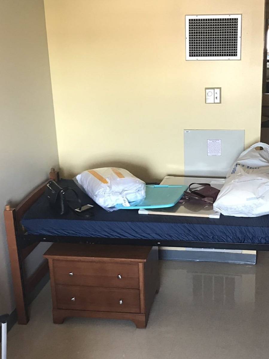 A small dorm bed with various items on top.