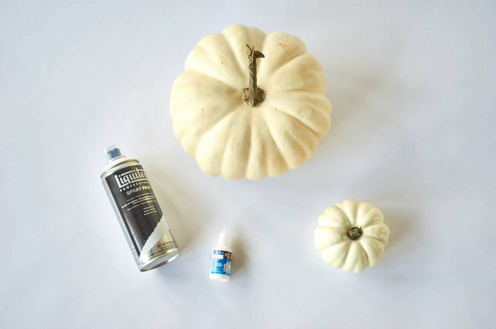 White pumpkins and spray on a white surface.