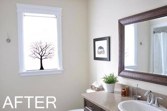 A tree image is on a frosted glass window in a bright white modem bathroom.