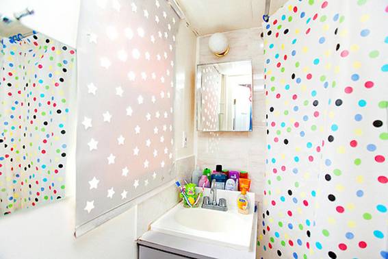 This busy bathroom features both a display of white stars and colorful polka dots that seem to match the bottles around the sink area.