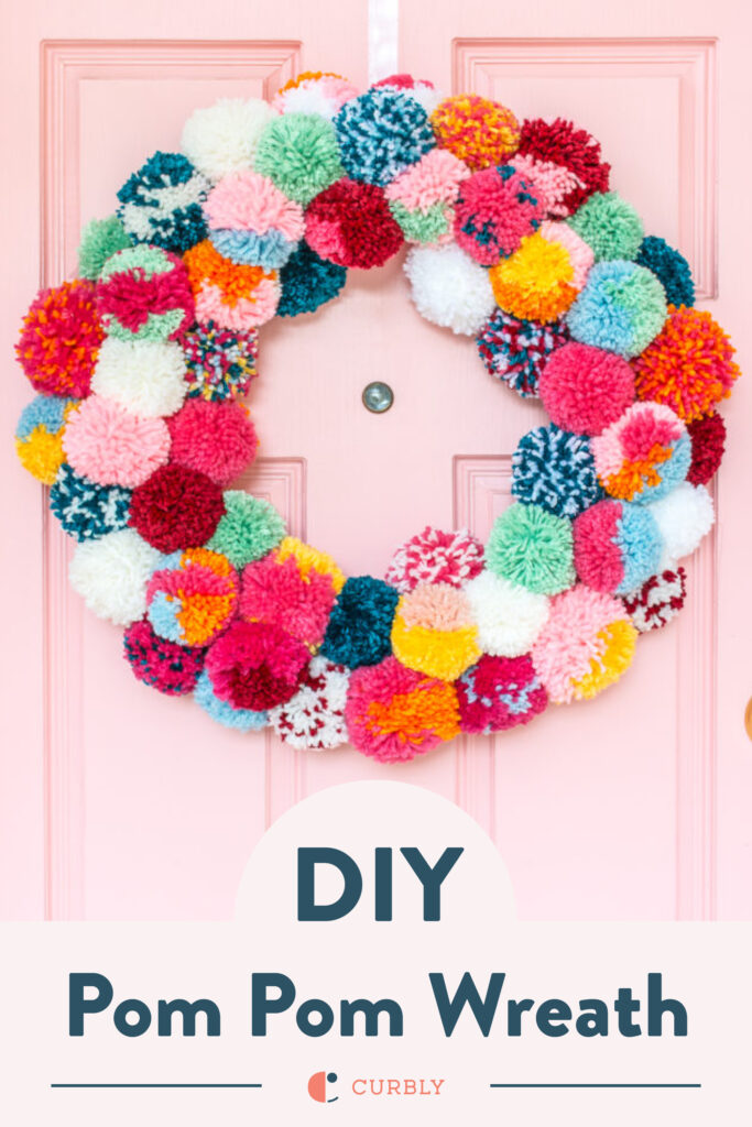 colorful pom pom wreath on a pink door