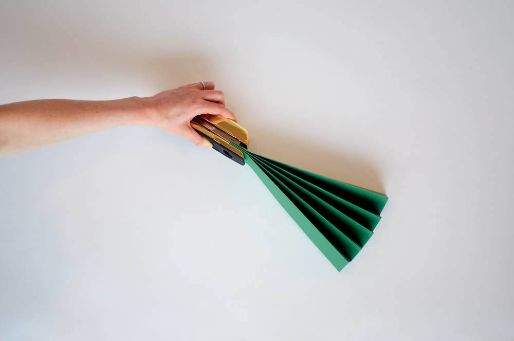 An arm is holding a small green crafted fan.