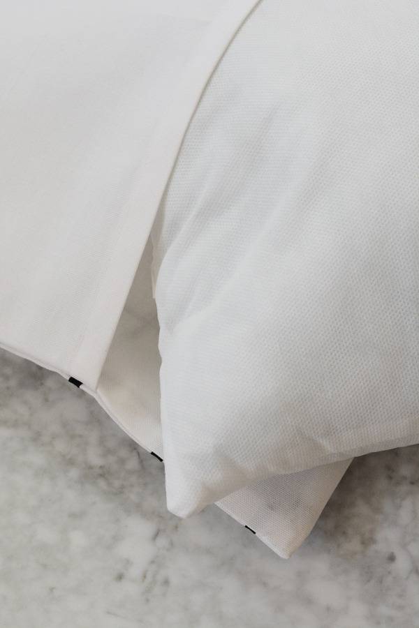 Cream colored sheets and pillows lay on the floor.