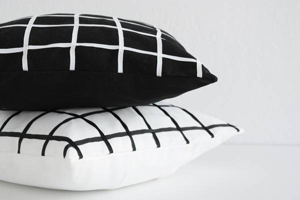 A black pillow with white squares stacked above a white pillow with black squares.