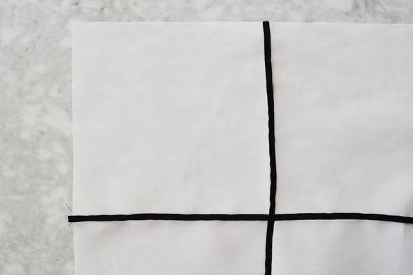 A black + plus sign dividing the white paper into equal fours on top of a gray and white counter top.