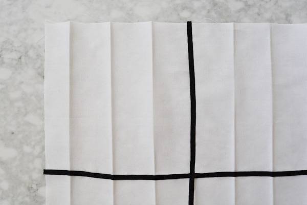 A piece of unfolded white paper with a black vertical line crossing a black horizontal line.