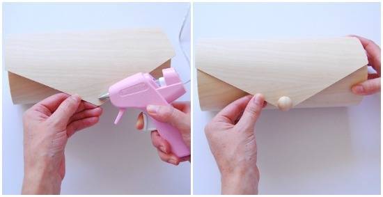 Person gluing a button of a wooden purse.